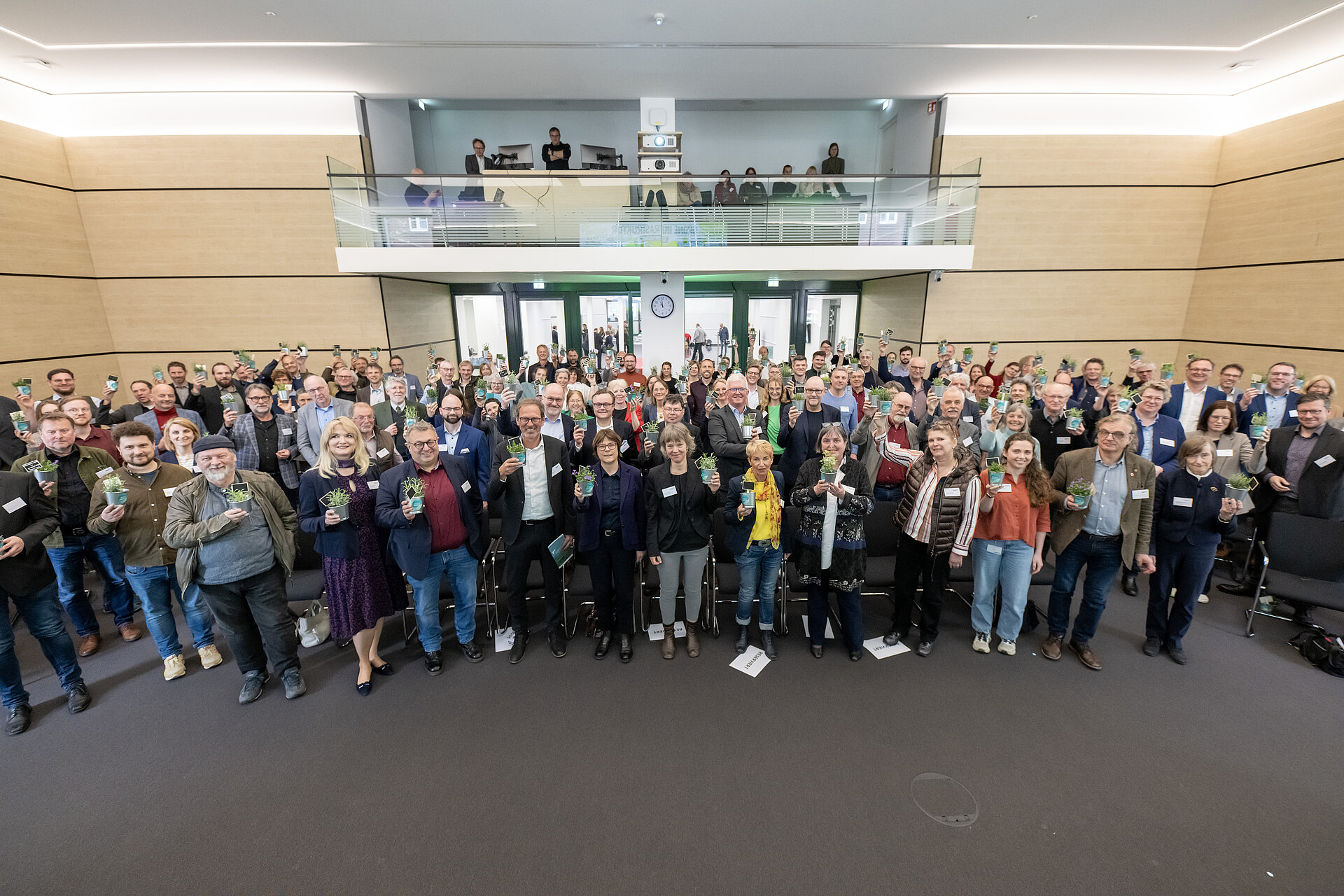 Gruppenbild aller Teilnehmenden im Plenarsaal mit Kräutertöpfchen in der Hand