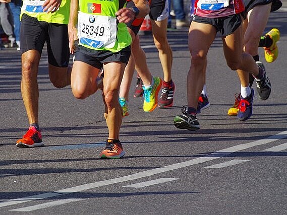 Das Foto zeigt mehrere Beine bei einem Marathonlauf.