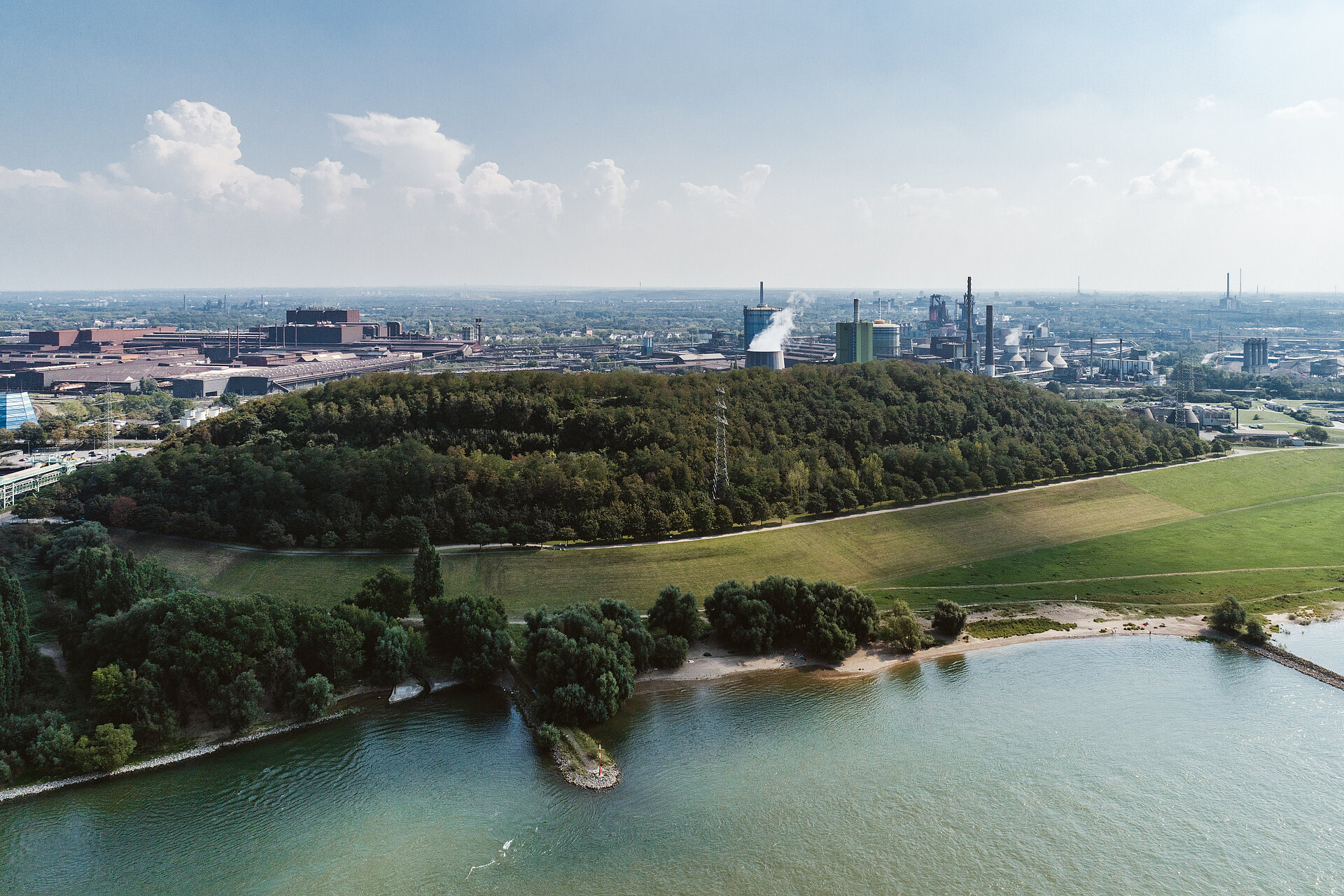 Im Westen erblickt man hinter dem Rhein, der nach Norden fließt, das ländlich geprägte Land des Niederrheins. 