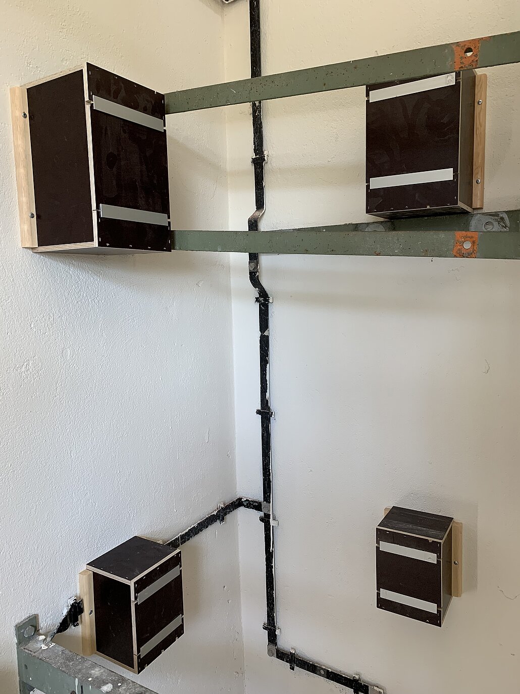 Blick aus dem Inneren des Artenschutzturms auf vier eingebaute, nach außen geöffnete Nistkästen