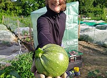 Eine Gärtnerin, die ihre Zucchini präsentiert