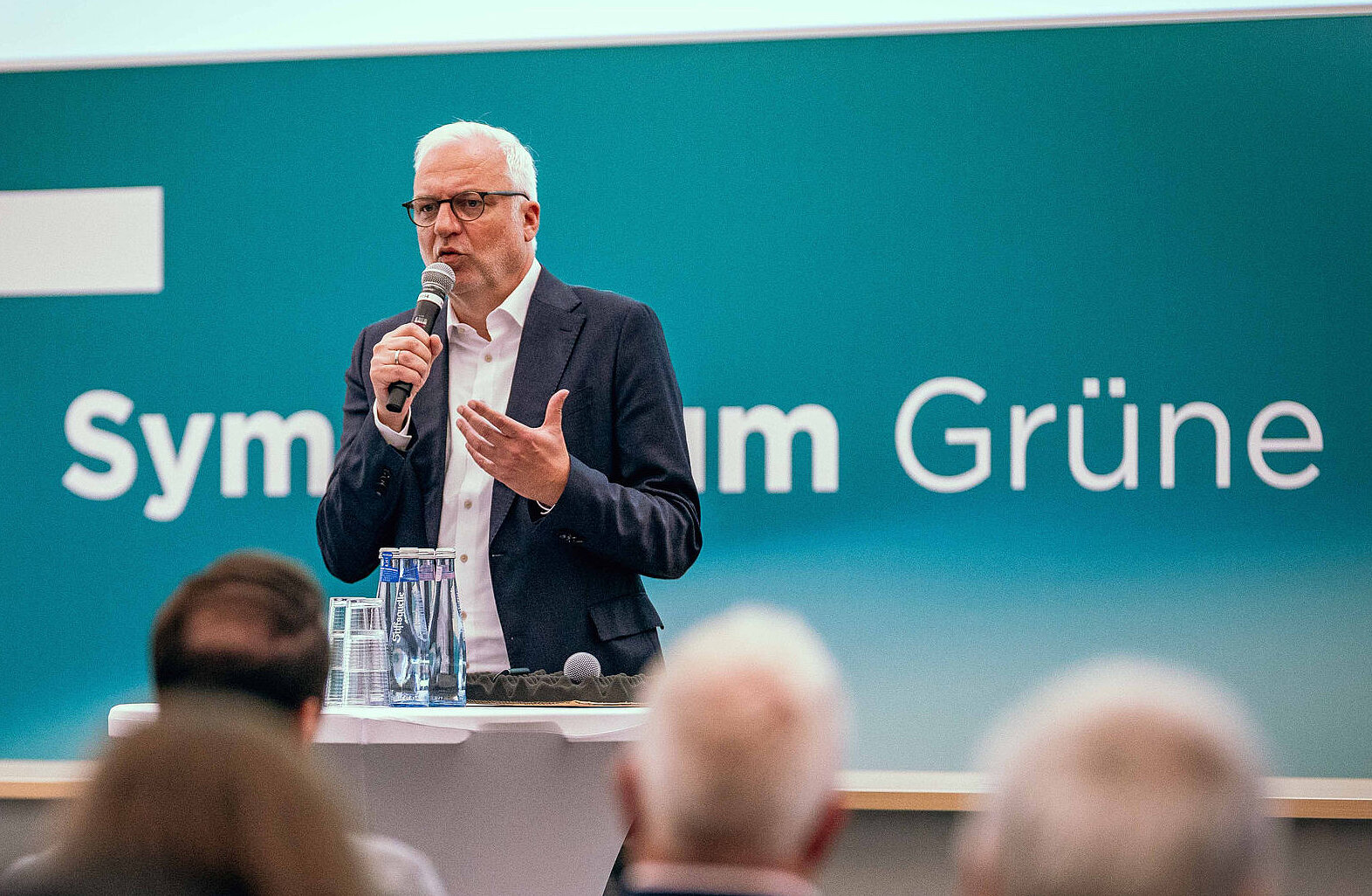 Garrelt Duin, Regionaldirekter des Regionalverbandes Ruhr (RVR), steht auf der Bühne des Symposiums Grüne Infrastruktur und hält ein Mikrofon in der Hand, im Vordergrund Publikum