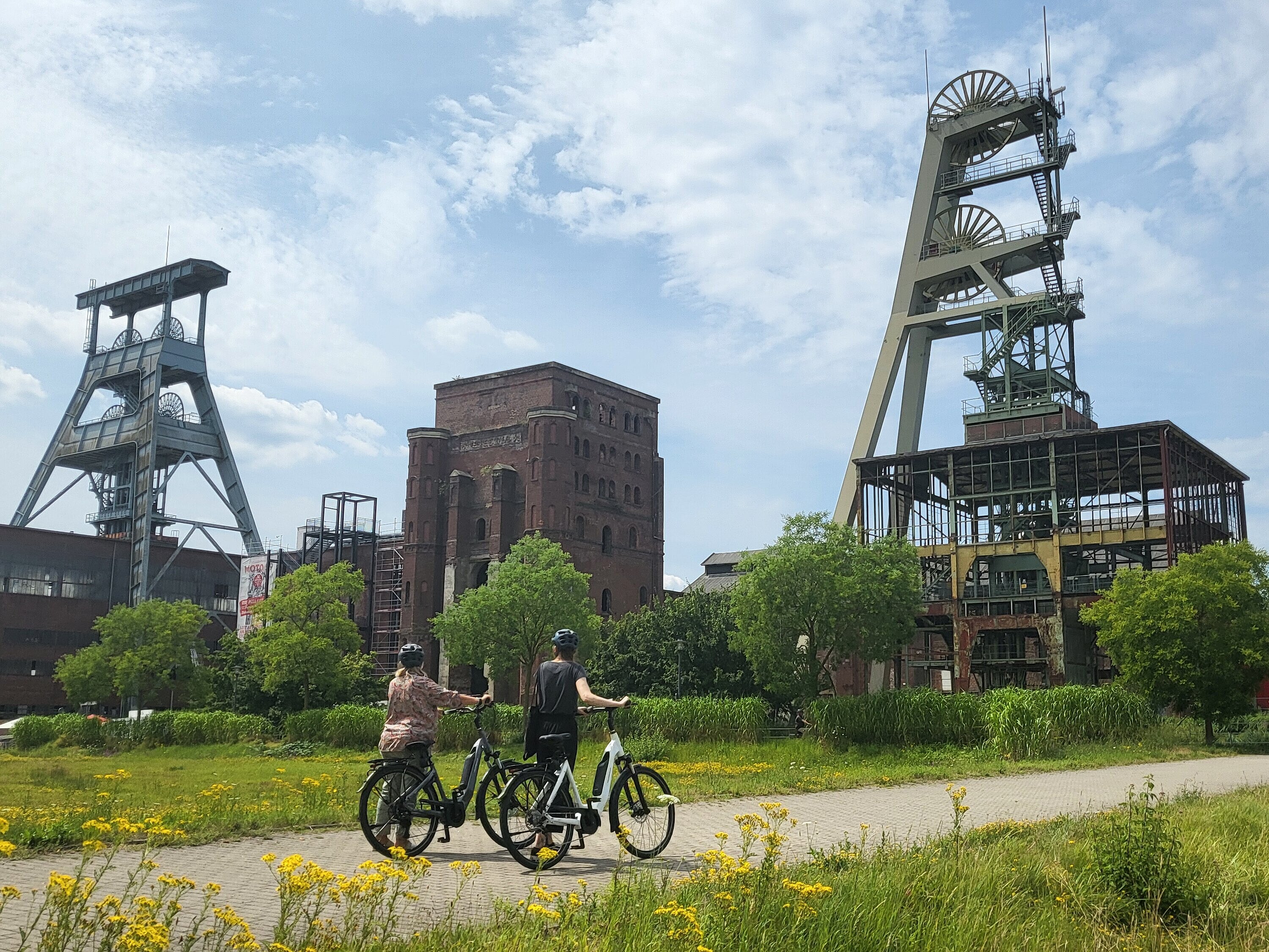 Zwei Personen fahren mit dem Fahrrad über das Gelände der ehemaligen Zeche Ewald.