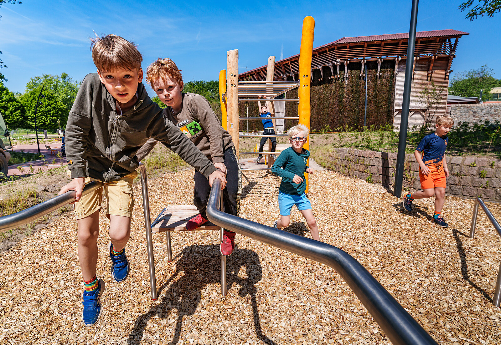 Zwei Jungs sitzen auf einem Klettergerüst. Im  Hintergrund spielen noch weitere Kinder