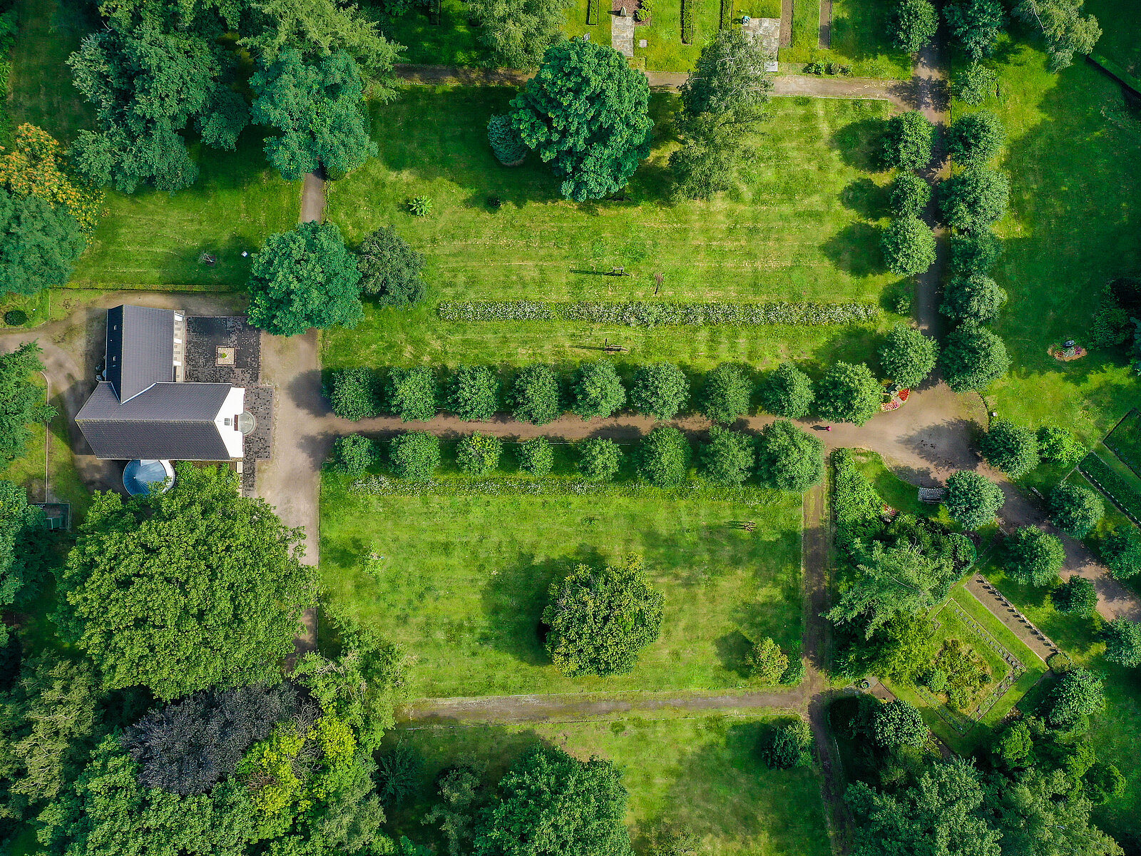 Luftbildaufnahme von einem Garten mit Haus und Baumallee zum Haus führend
