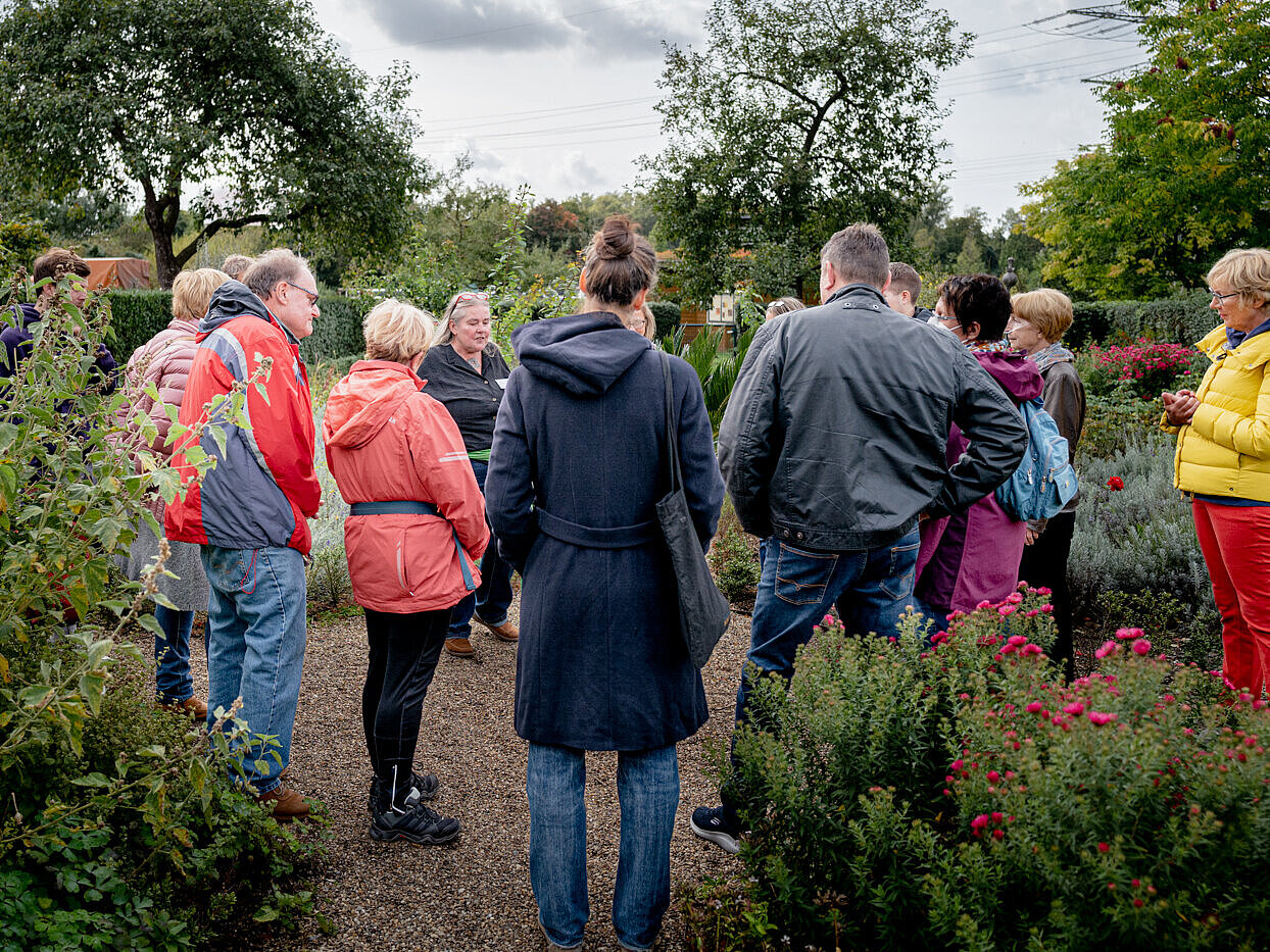 Eine Gruppe Menschen stehen bei einer Führung im Bauerngarten