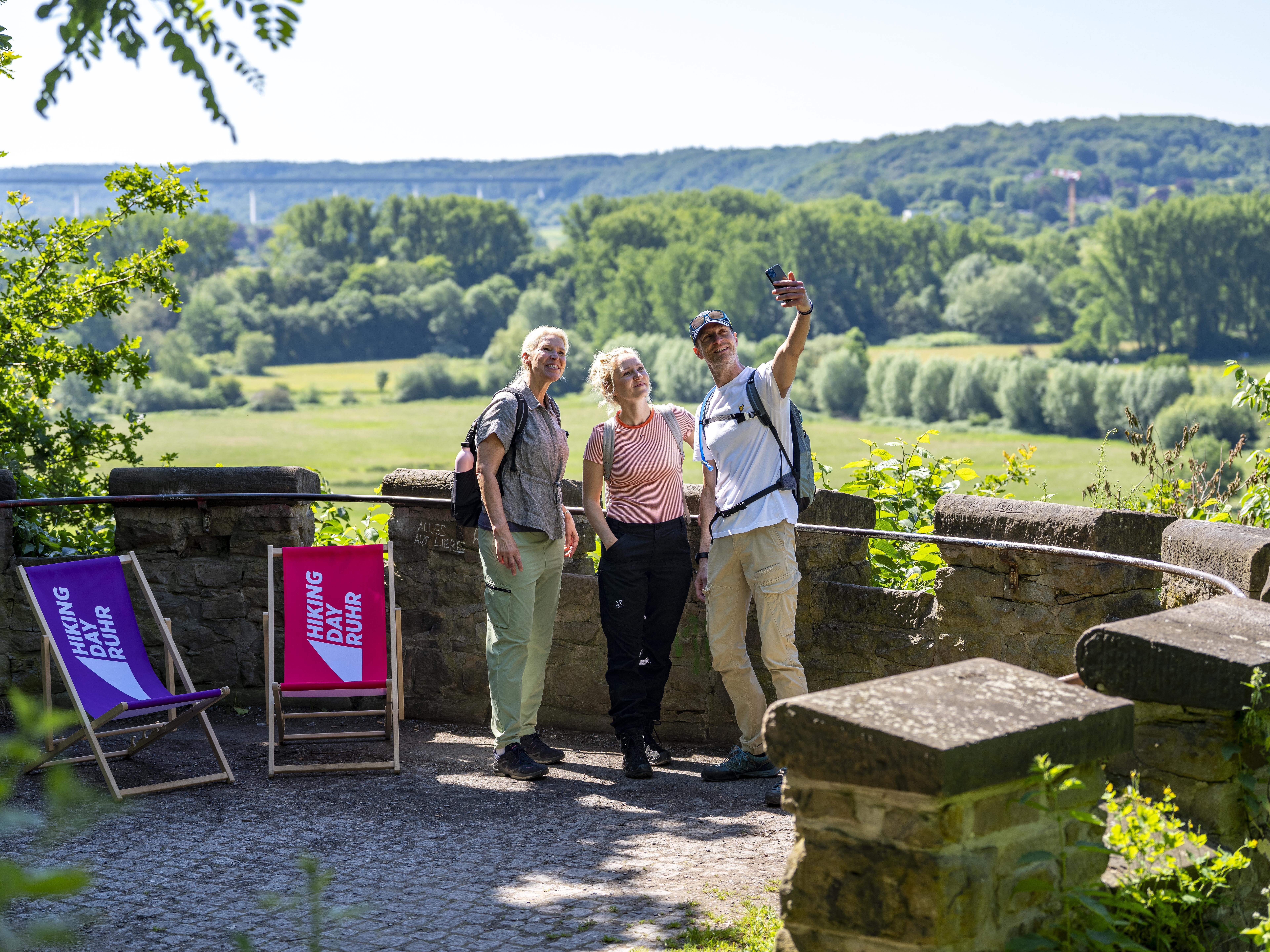 Drei Personen machen vor einem Panorama ein Selfie. 