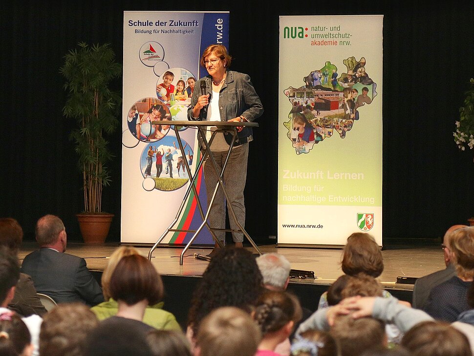 Regionaldirektorin auf der Bühne mit Mikro in der Hand