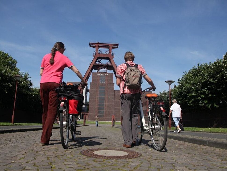 Zwei Radtouristen schieben ihr Rad über das Zollvereingelände. Foto: RVR