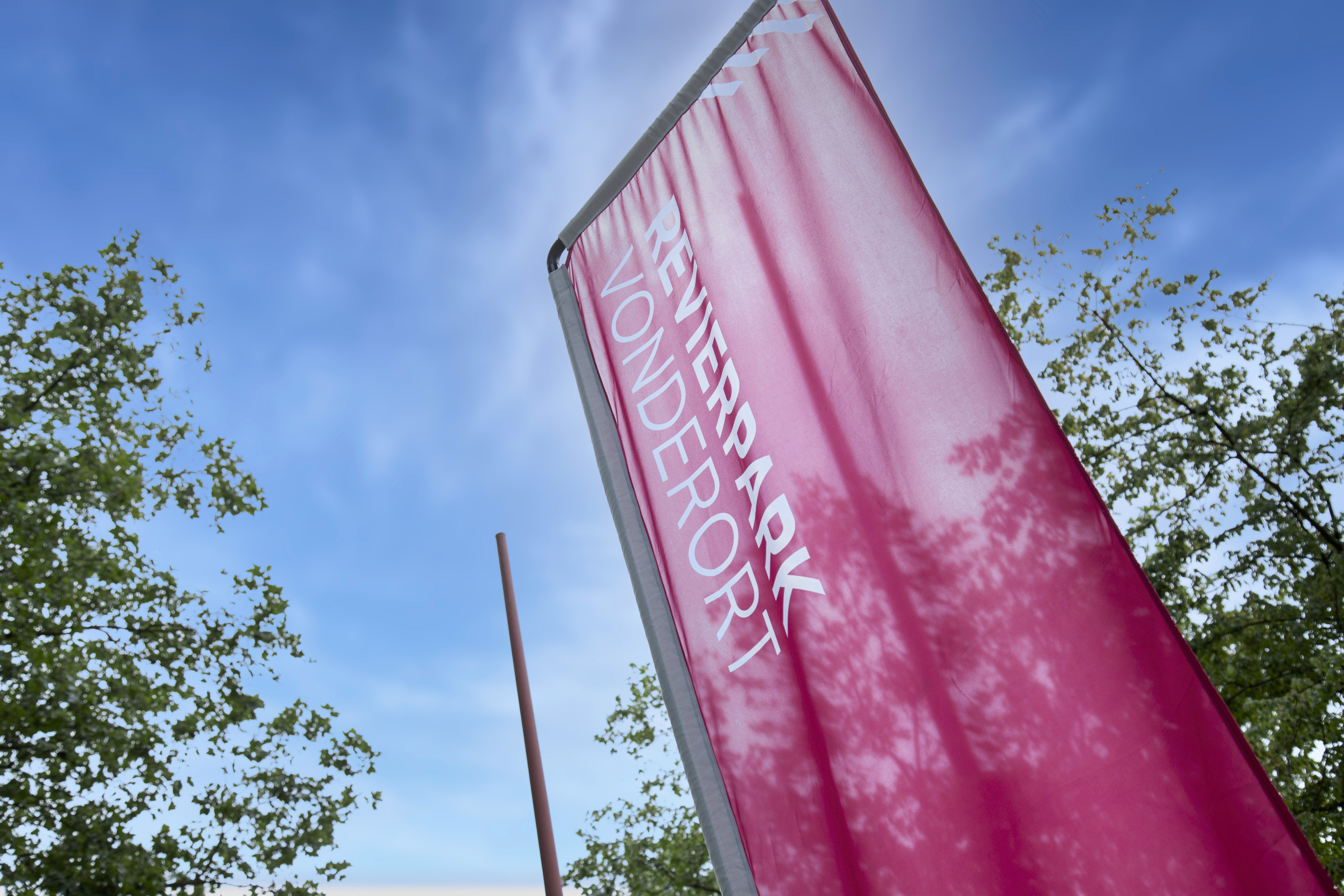 Fahne mit der Aufschrift Revierpark Vonderort vor blauem Himmel.