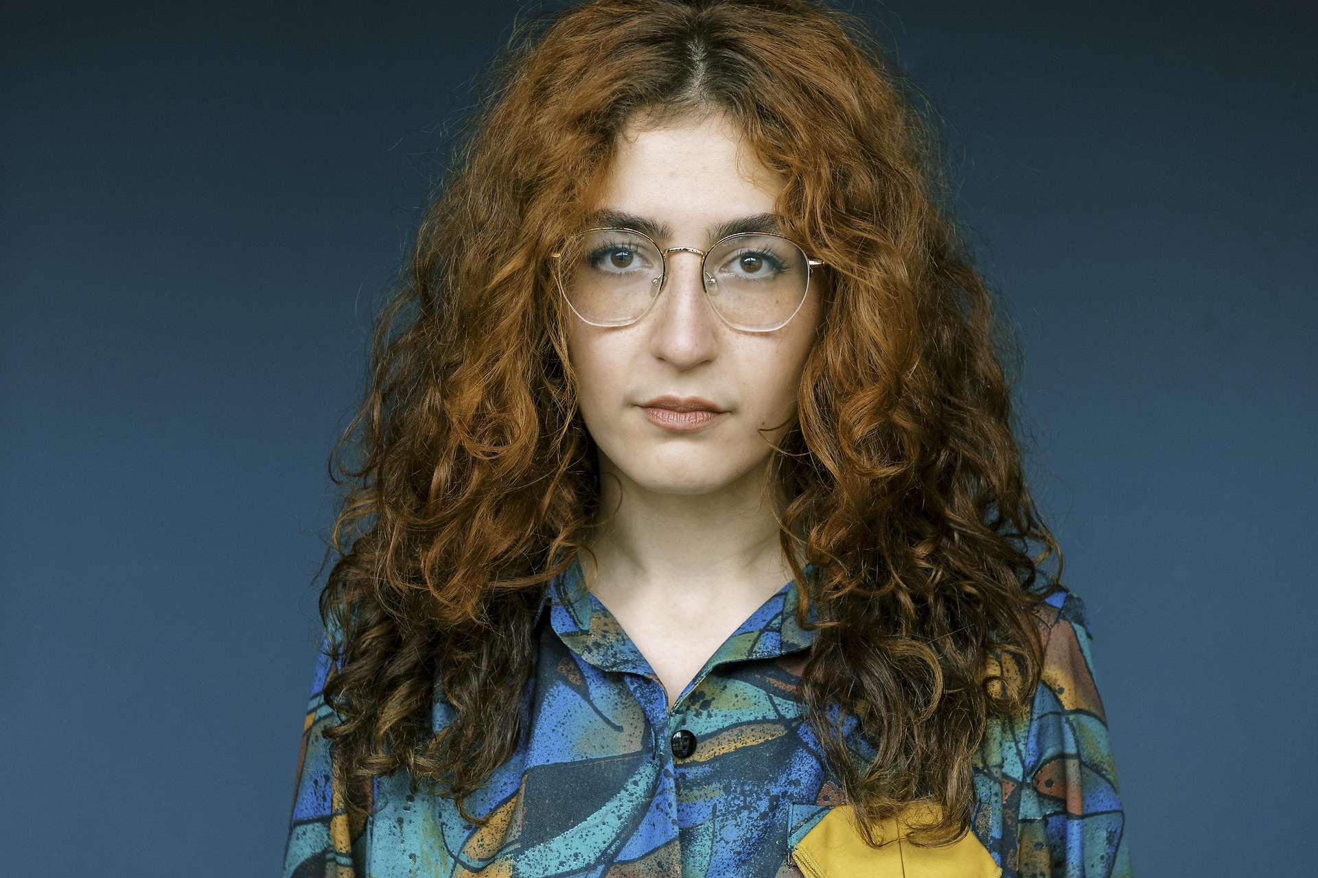 Miedya Mahmod blickt in die Kamera vor blauem Hintergrund.