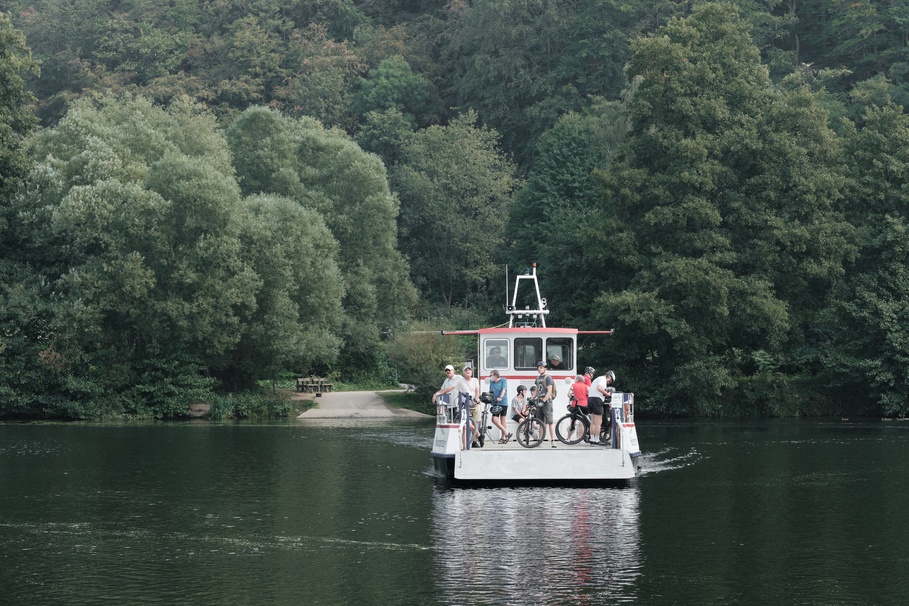 Kleine Fähre fährt mit Radfahrern auf der Ruhr
