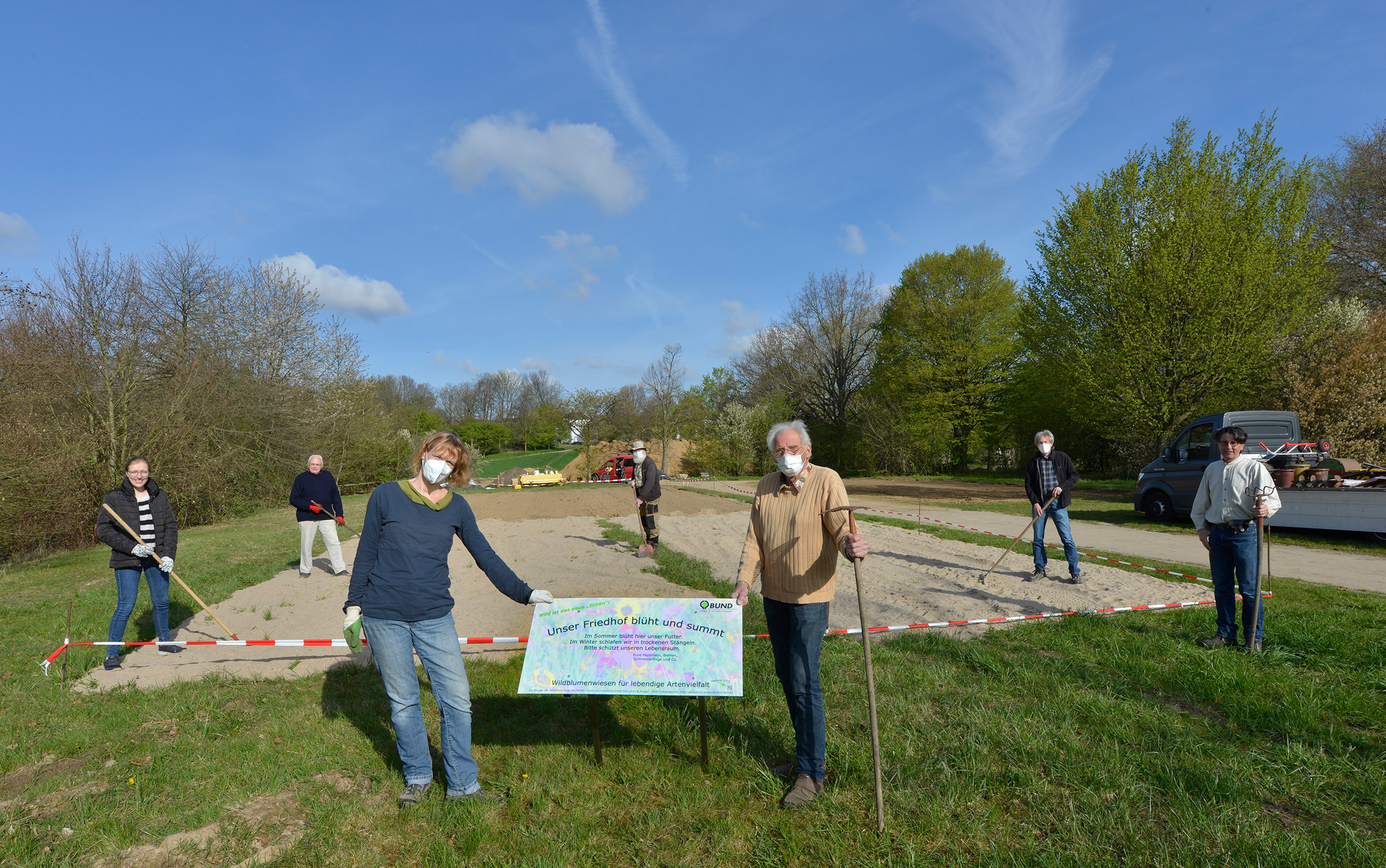 Freiwillige Helfer, die um eine Fläche auf dem Terrassenfriedhof Schöebbeck stehen und eine Karte halten
