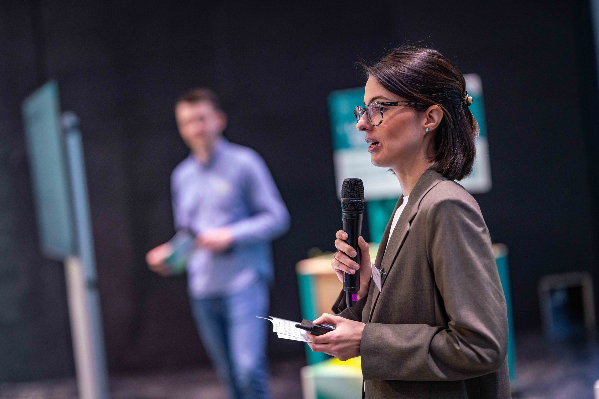 Davina Mikutta von IT.NRW steht auf der Bühne des Netzwerktags Grüne Infrastruktur und hält ein Mikrofon in der Hand.