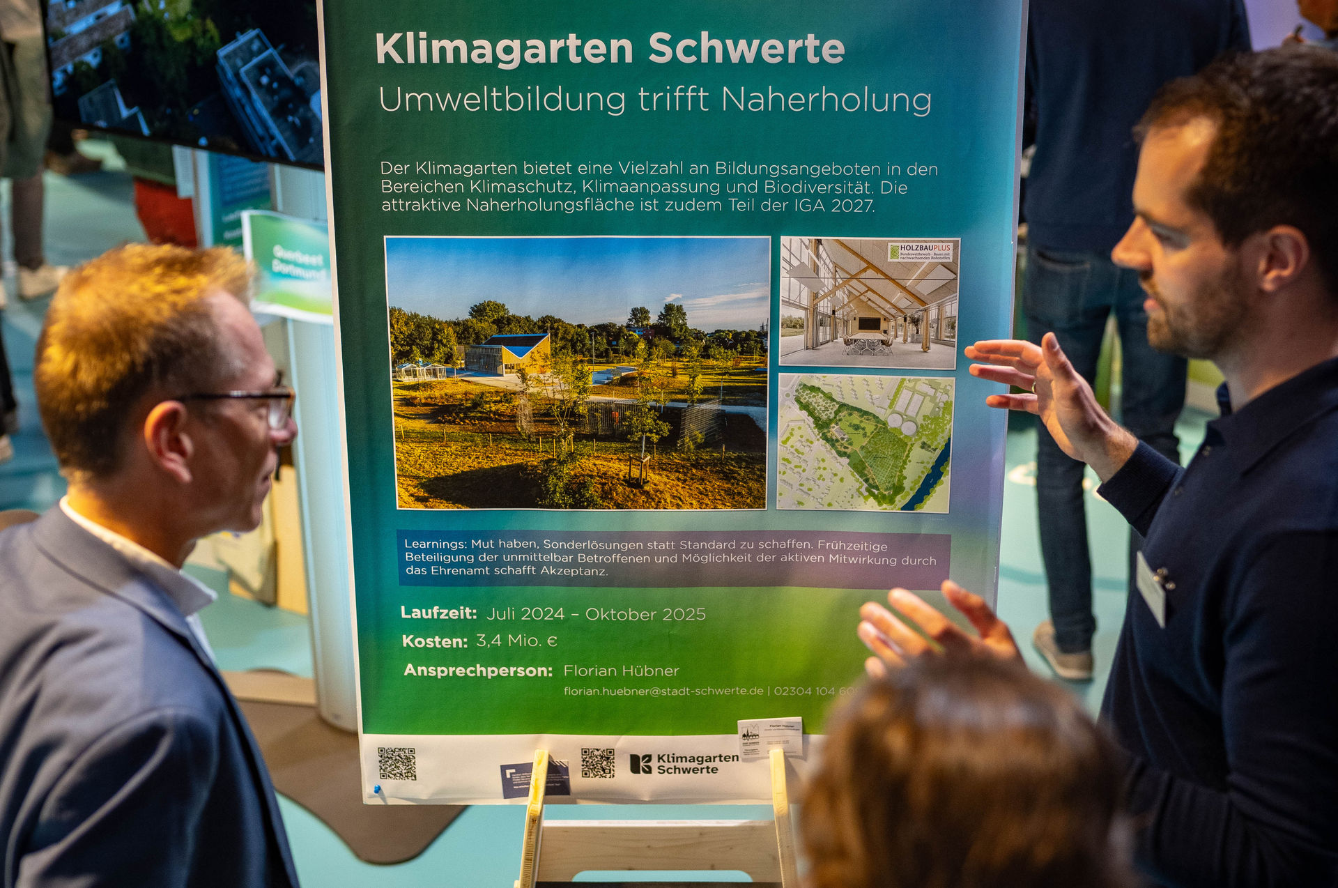 Drei Personen stehen vor einem Plakat mit Informationen zum Projekt "Klimagarten Schwerte".