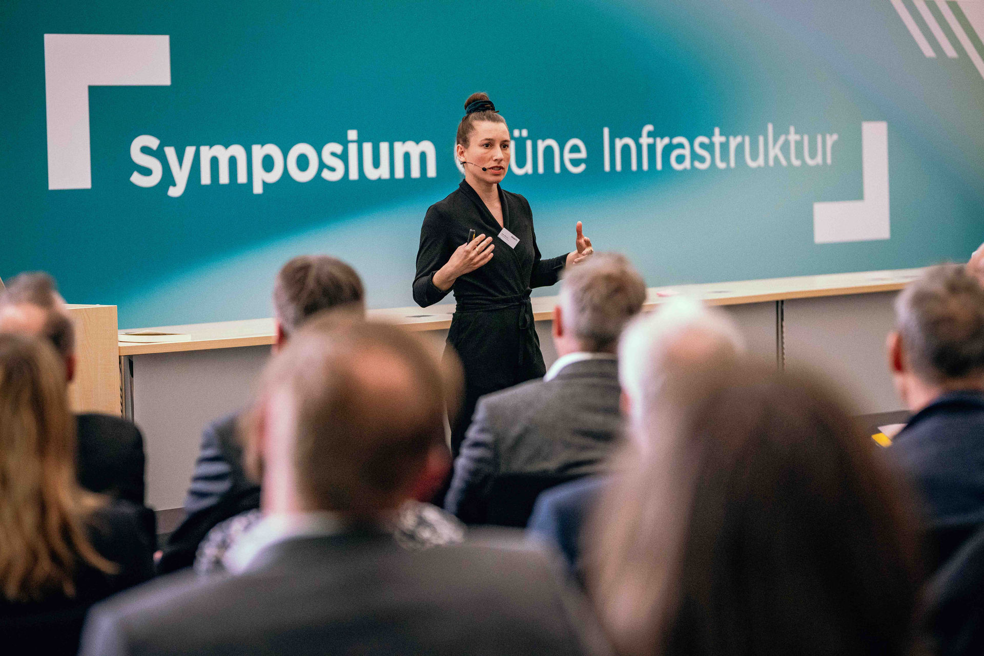 Zukunftsforscherin, Gründerin und Autorin Jule Bosch steht auf der Bühne des Symposiums Grüne Infrastruktur, im Vordergrund Publikum.