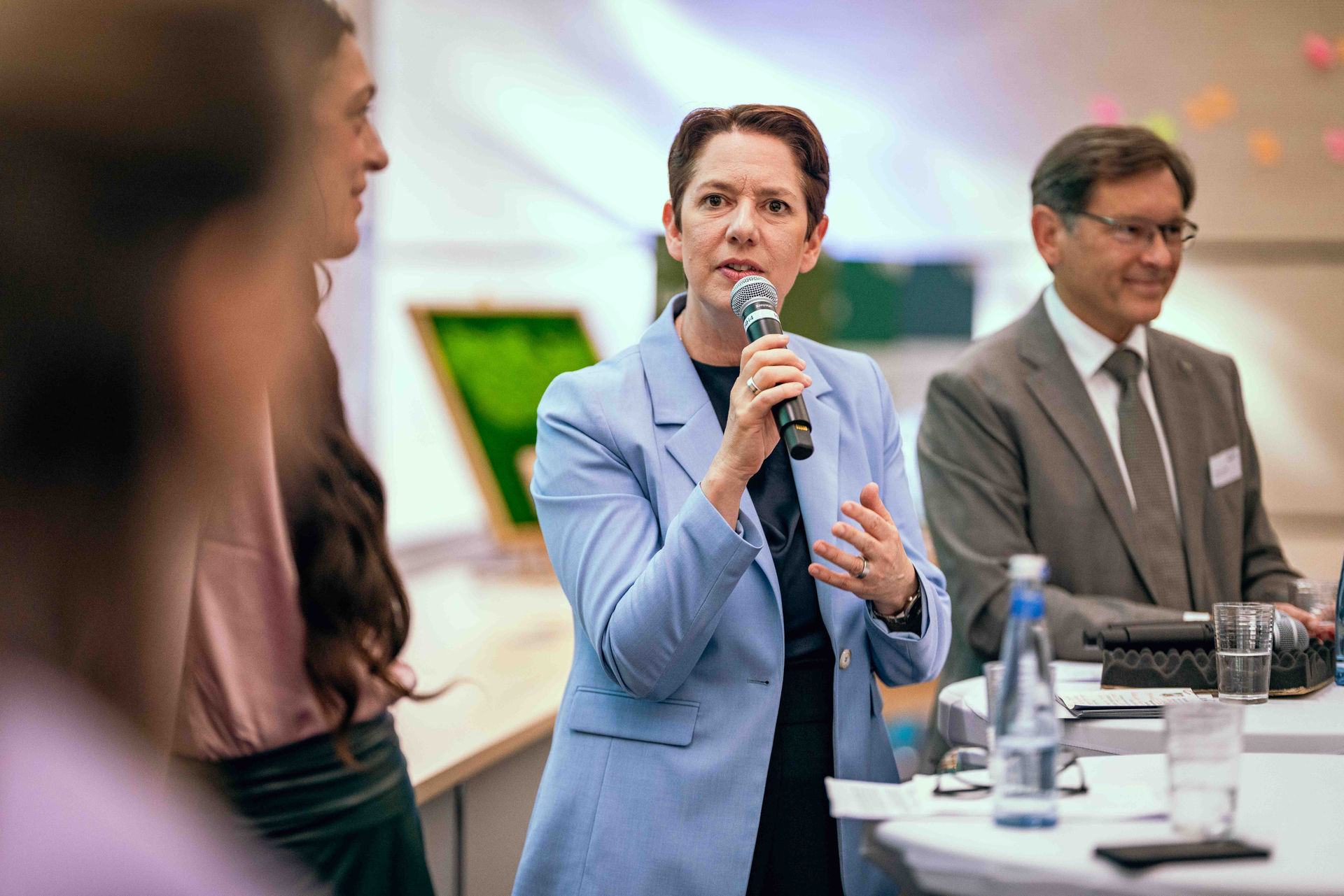ilke Gorißen, Ministerin für Landwirtschaft und Verbraucherschutz des Landes Nordrhein-Westfalen, steht auf der Bühne des Symposiums Grüne Infrastruktur und hält ein Mikrofon in der Hand.