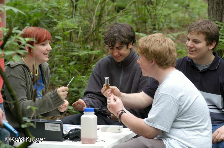 Eine Gruppe von Jugendlichen schauen auf Reagenzgläser gefüllt mit Wasserproben
