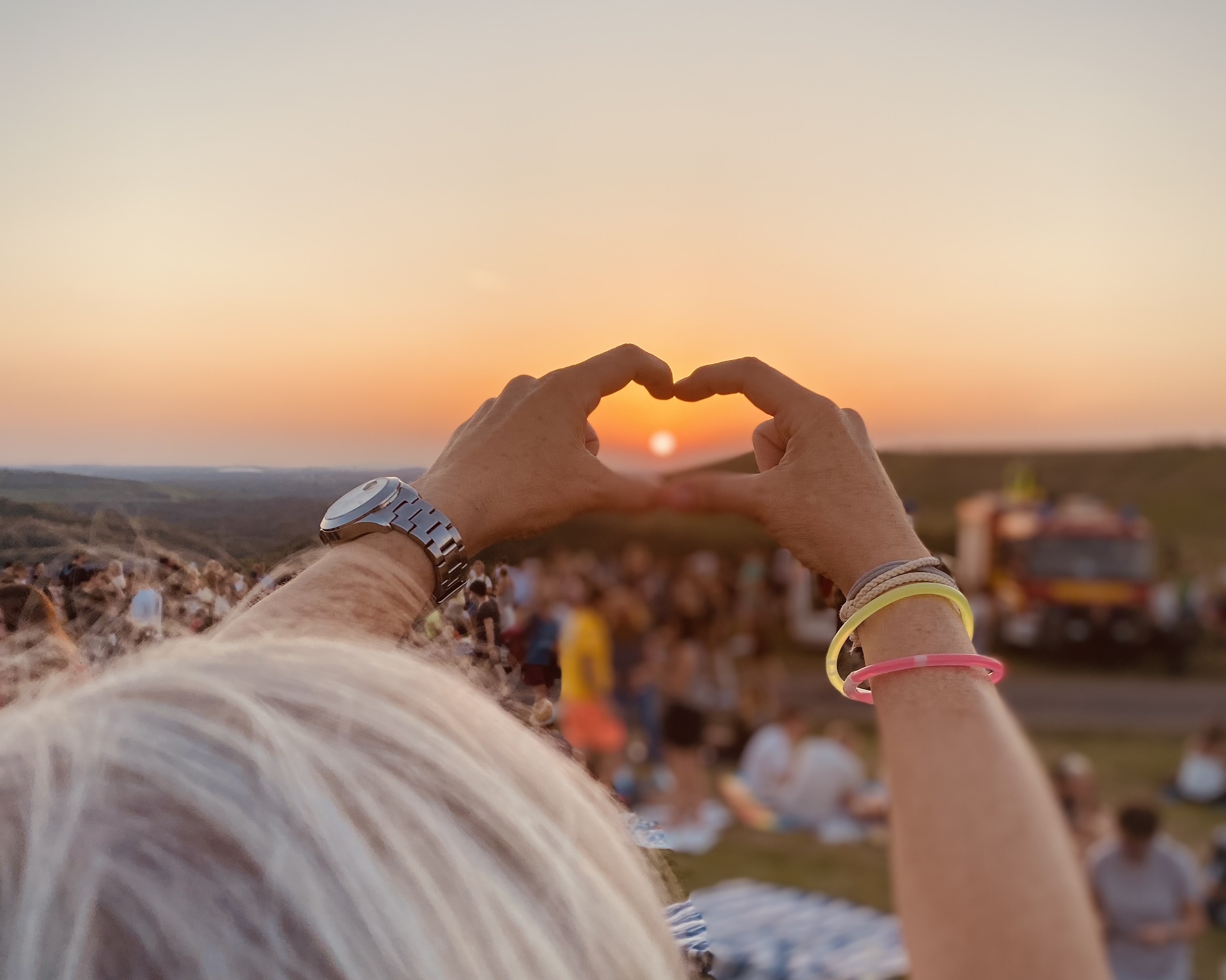 Sonnenuntergang auf der Halde Hoheward. Eine Hand formt ein Herz in Richtung Sonne. 
