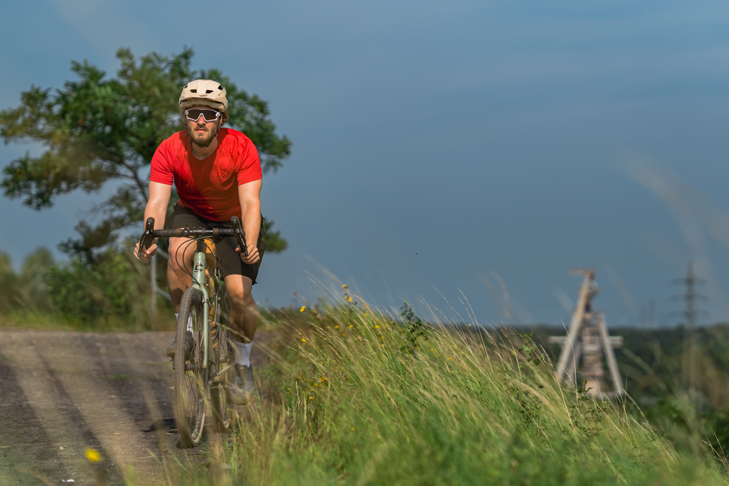 Radfahrer fährt der Kamera auf der Halde entgegen. Umgeben von Natur.