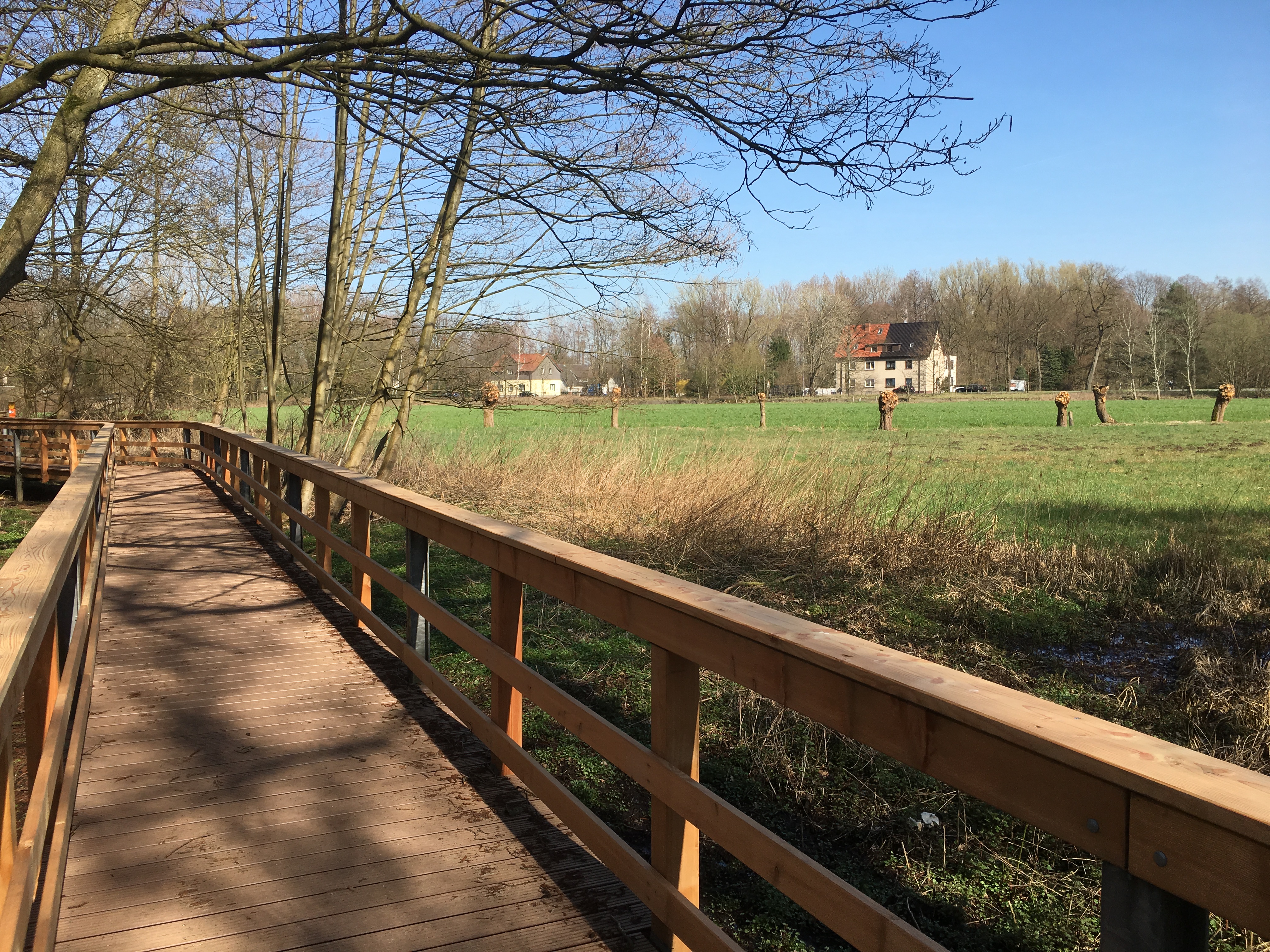 Brücke im Naturschutzgebiet "Die Brücke" in Marl mit Blick über eine grüne Freifläche.