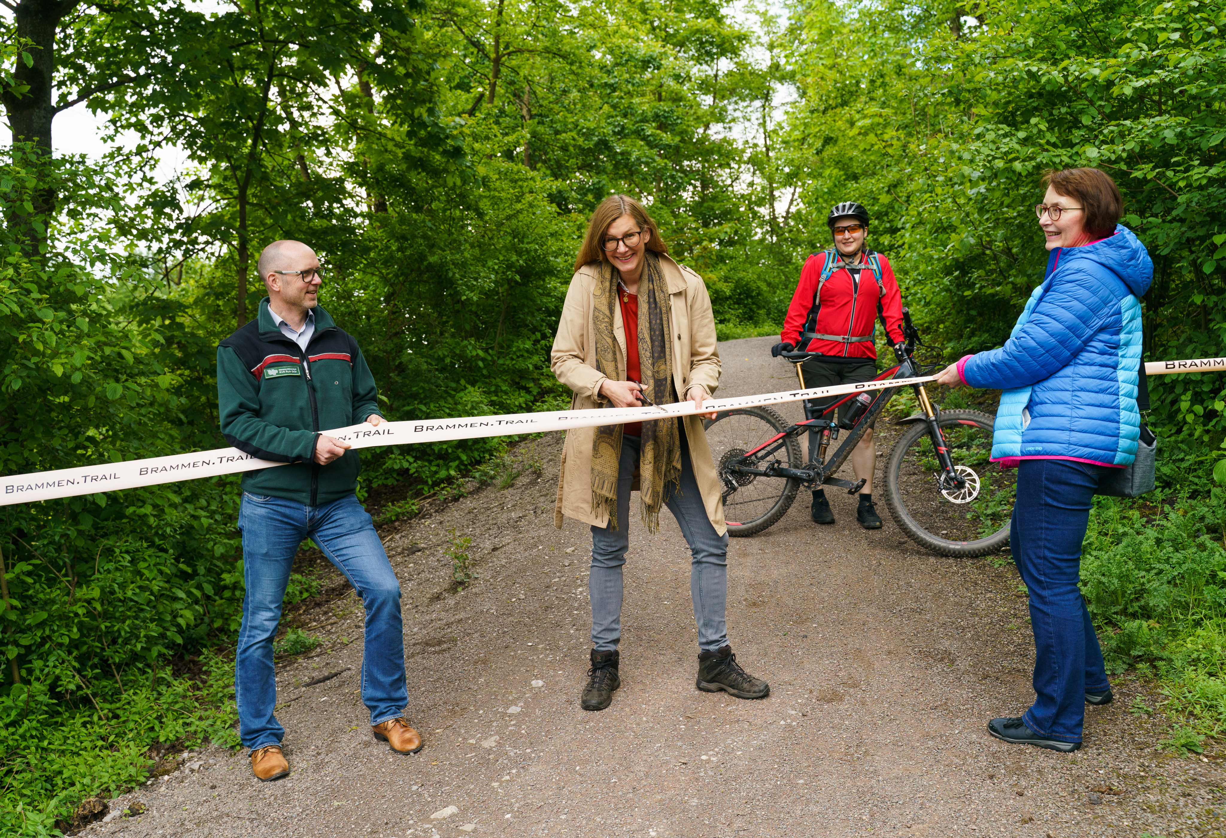 Der MTB-Trail ist eröffnet: Holger Böse, Fachbereichsleiter von RVR Ruhr Grün, Nina Frense, RVR-Bereichsleiterin Umwelt und Grüne Infrastruktur, XX und Angelika Siepmann, Fachbereichsleiterin Umweltamt Stadt Essen, geben den Weg frei.