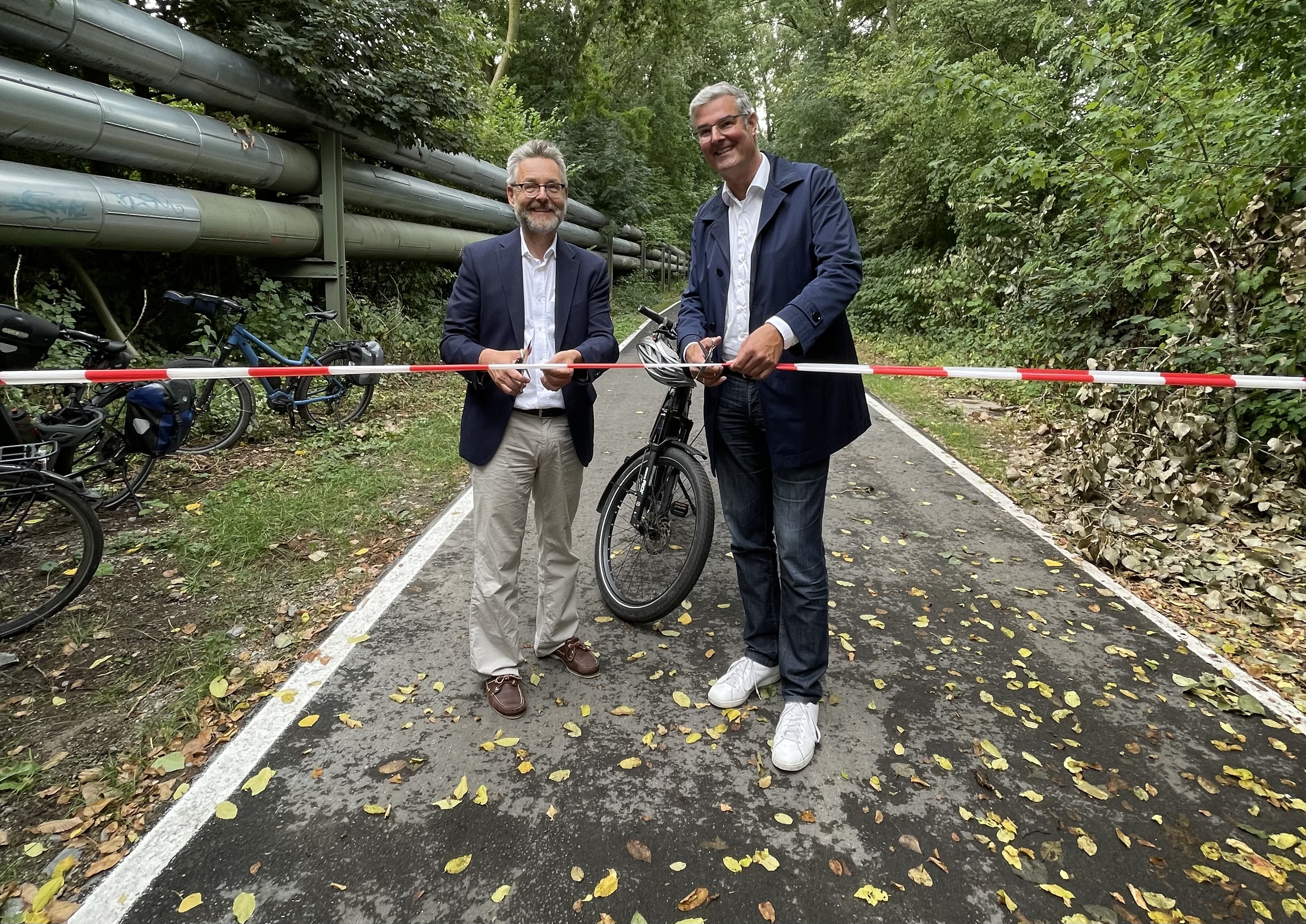 Dr. Markus Bradtke, Stadt Bochum (links), und Markus Schlüter, stellvertretender RVR-Regionaldirektor, geben den Weg frei von der Amtmann-Ibing-Straße in Bochum-Gerthe bis zur Sechs-Brüder-Straße in Bochum-Hordel.