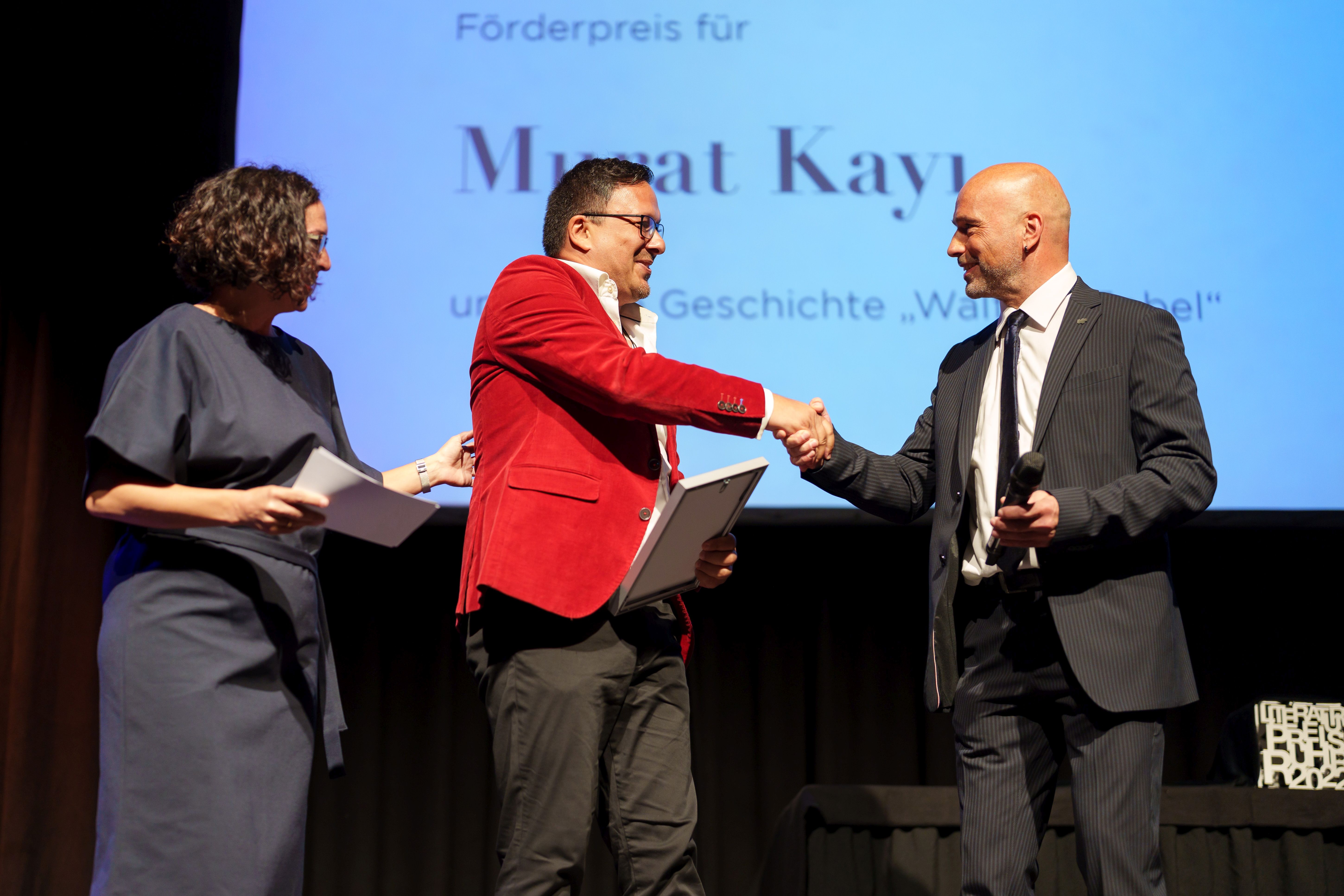 Förderpreisträger Murat Kayi mit Jörg Obereiner, Vorsitzender des RVR-Ausschusses Kultur, Sport und Vielfalt (links) und der Moderatorin Elif Senel (links).