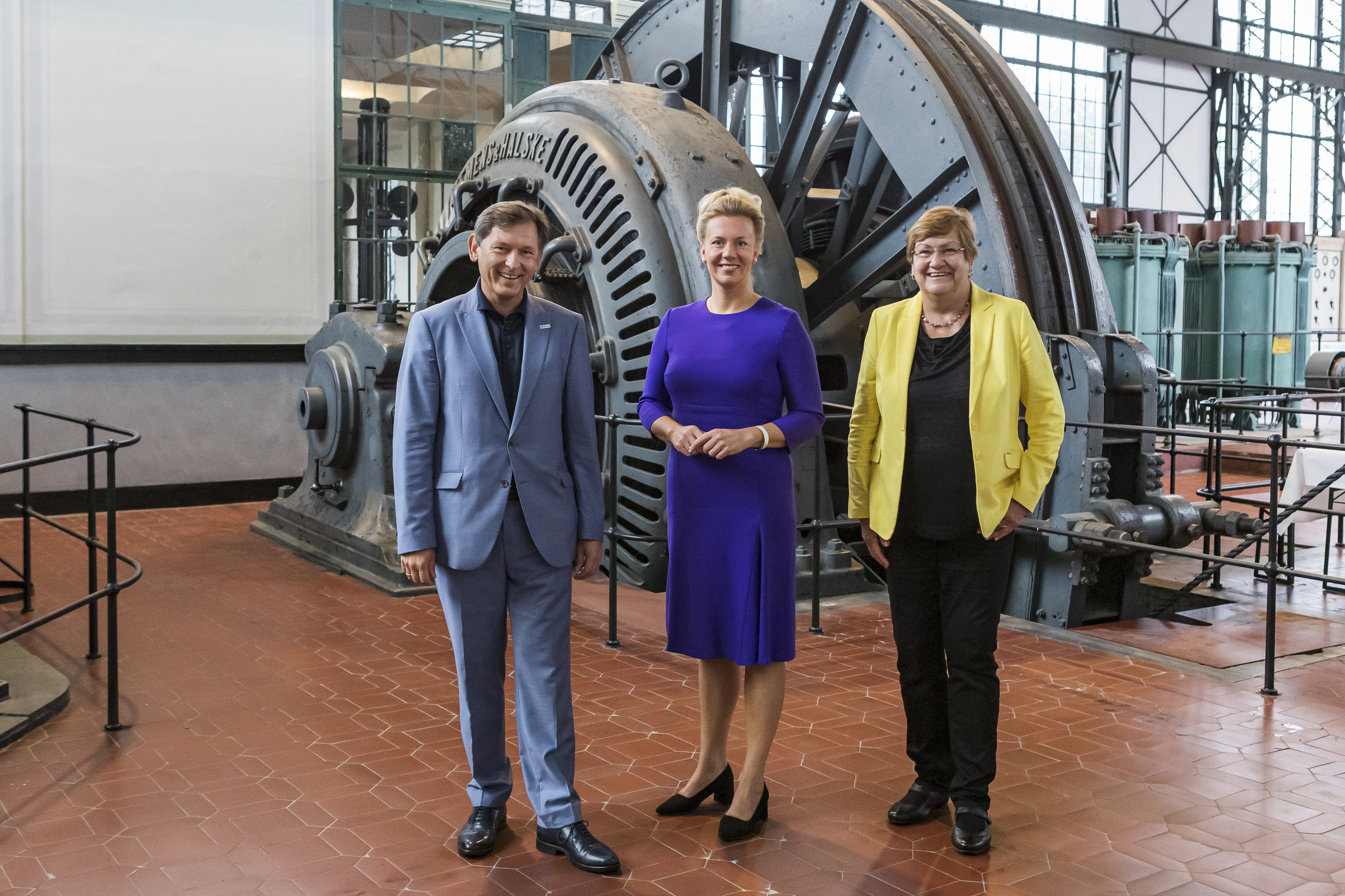 Drei Personen stehende vor großen Maschinen im Industriemuseum
