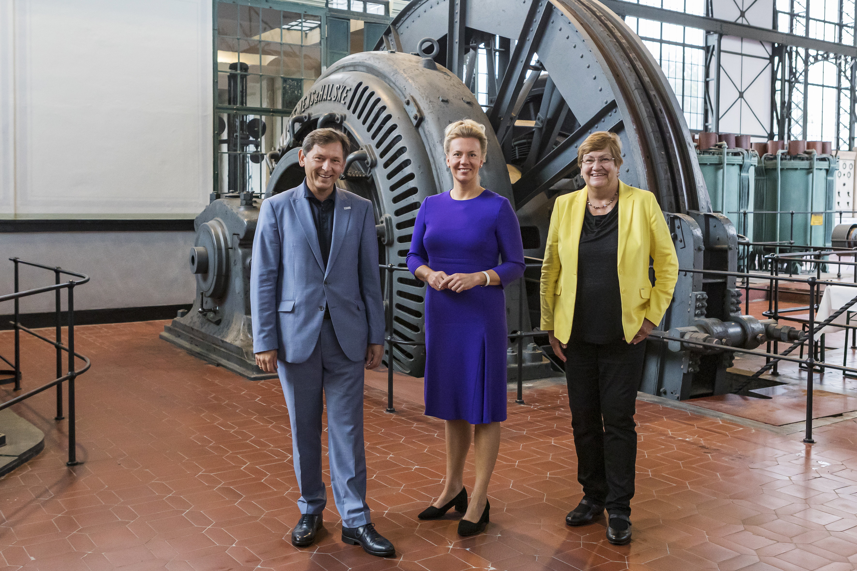 Drei Personen stehende vor großen Maschinen im Industriemuseum