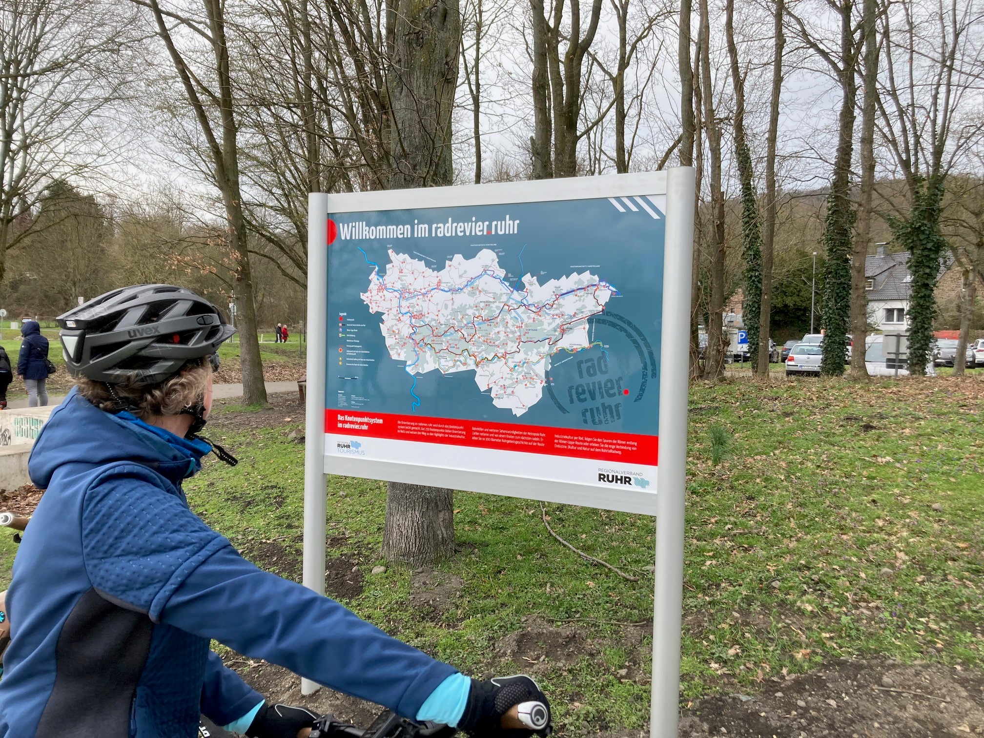 Mann mit Fahrradhelm schaut auf die Informationstafel