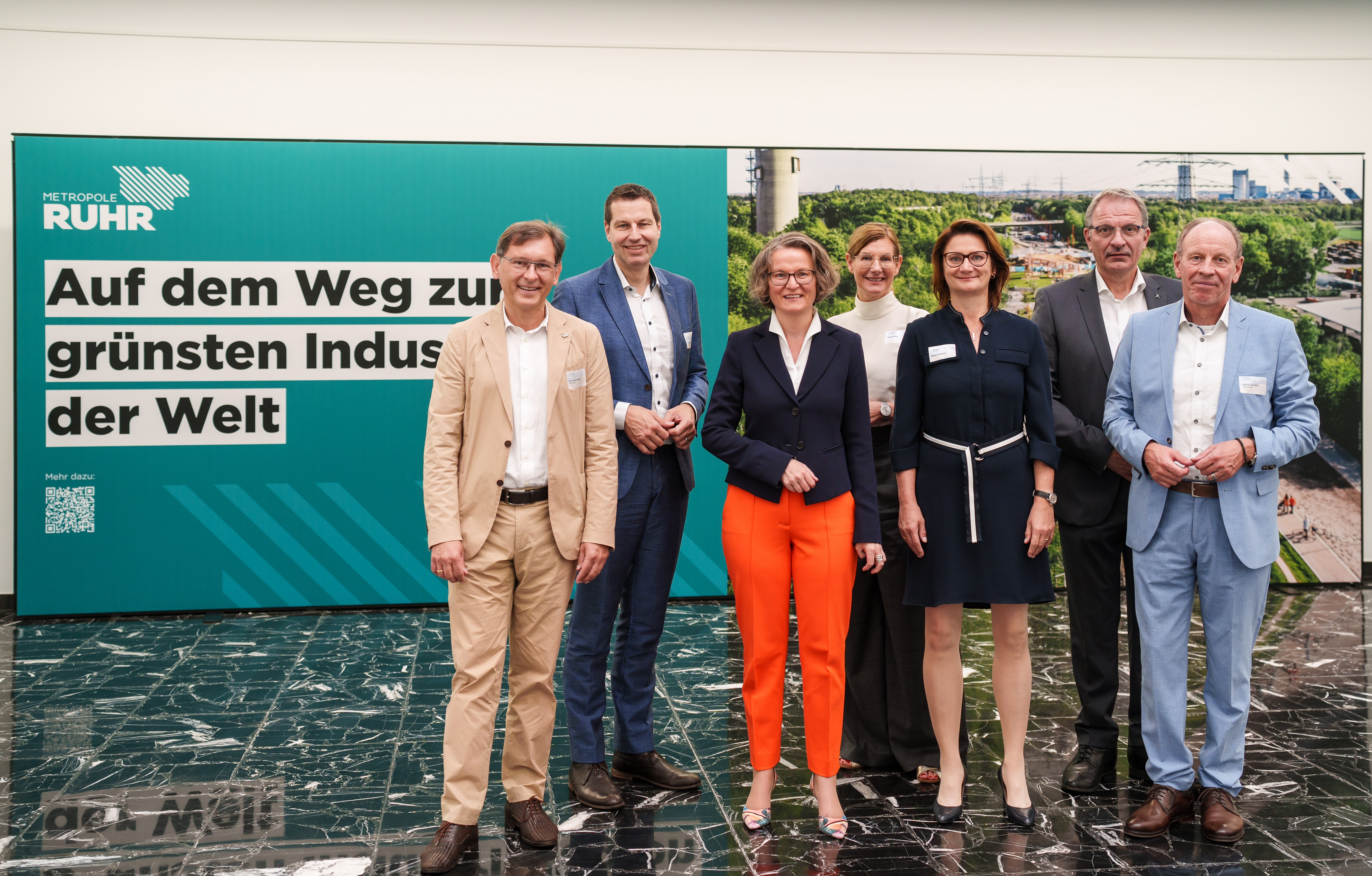 Gruppe stehend vor Banner mit Aufschrift "Grünste Industrieregion der Welt"