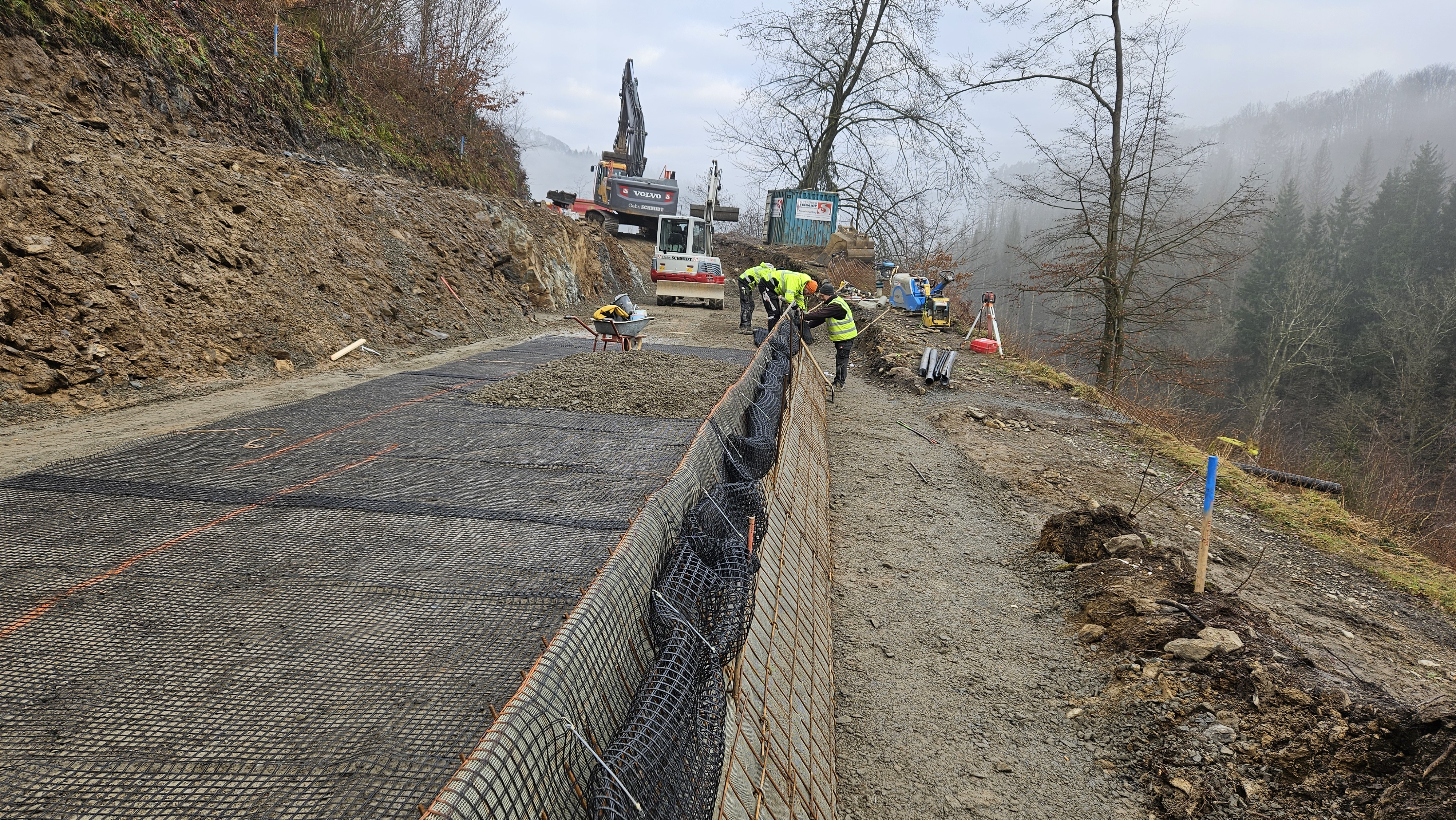 Zwei Bagger und mehrere Bauarbeiter an der Straße. 