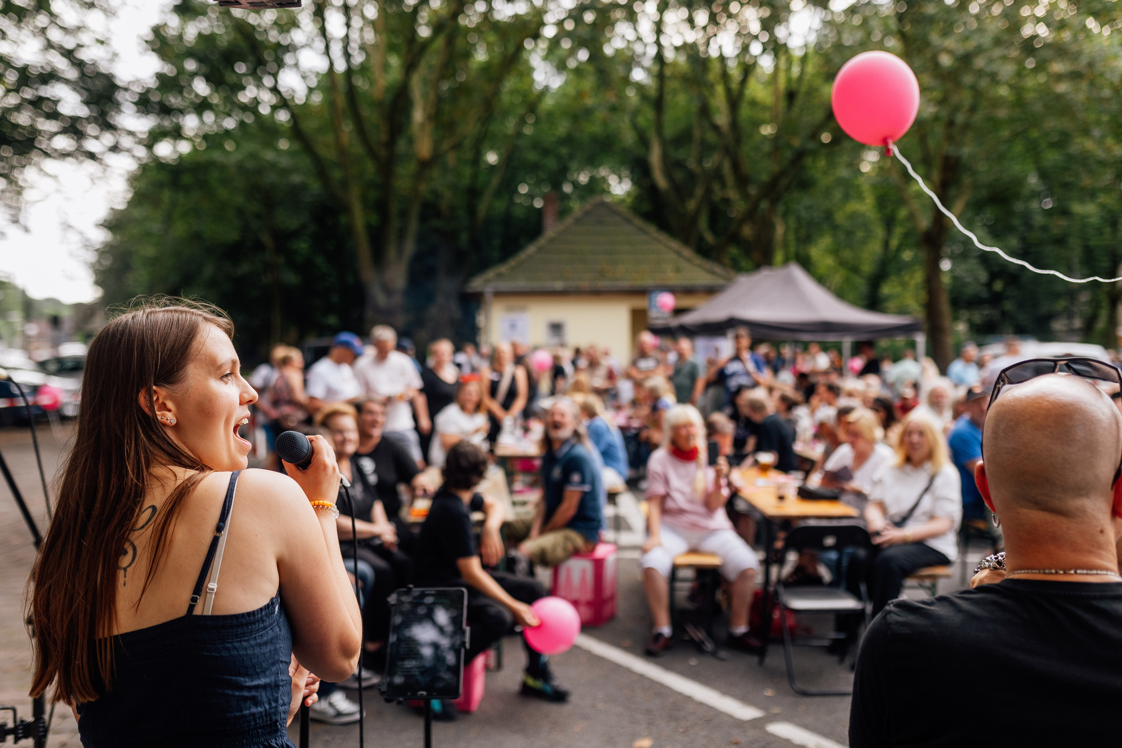 Künstlerin singt in ein Mikrofon. Im Hintergrund zeigt das Bild das Publikum. 