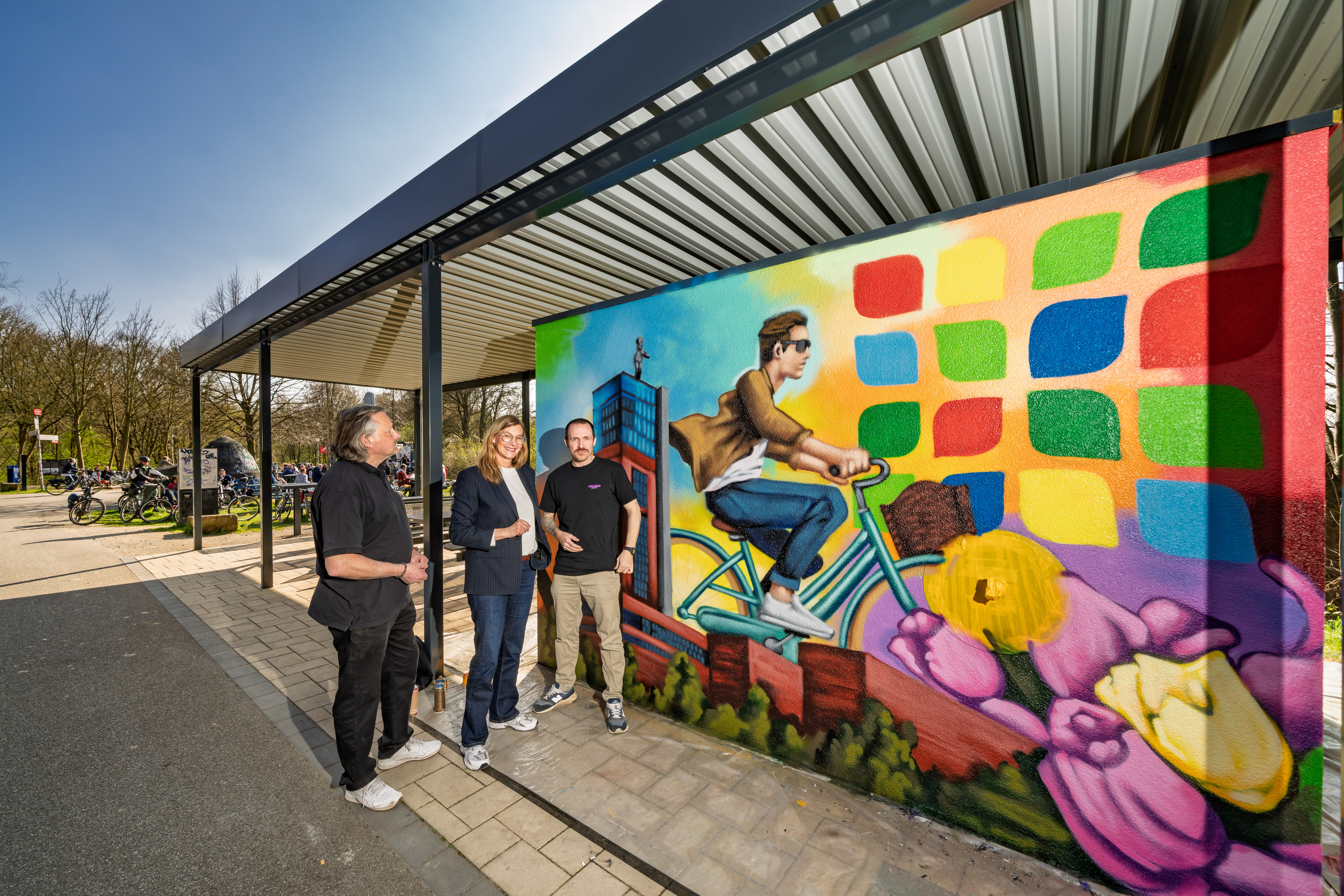 Drei Personen vor einer bunten Graffiti-Wand. 