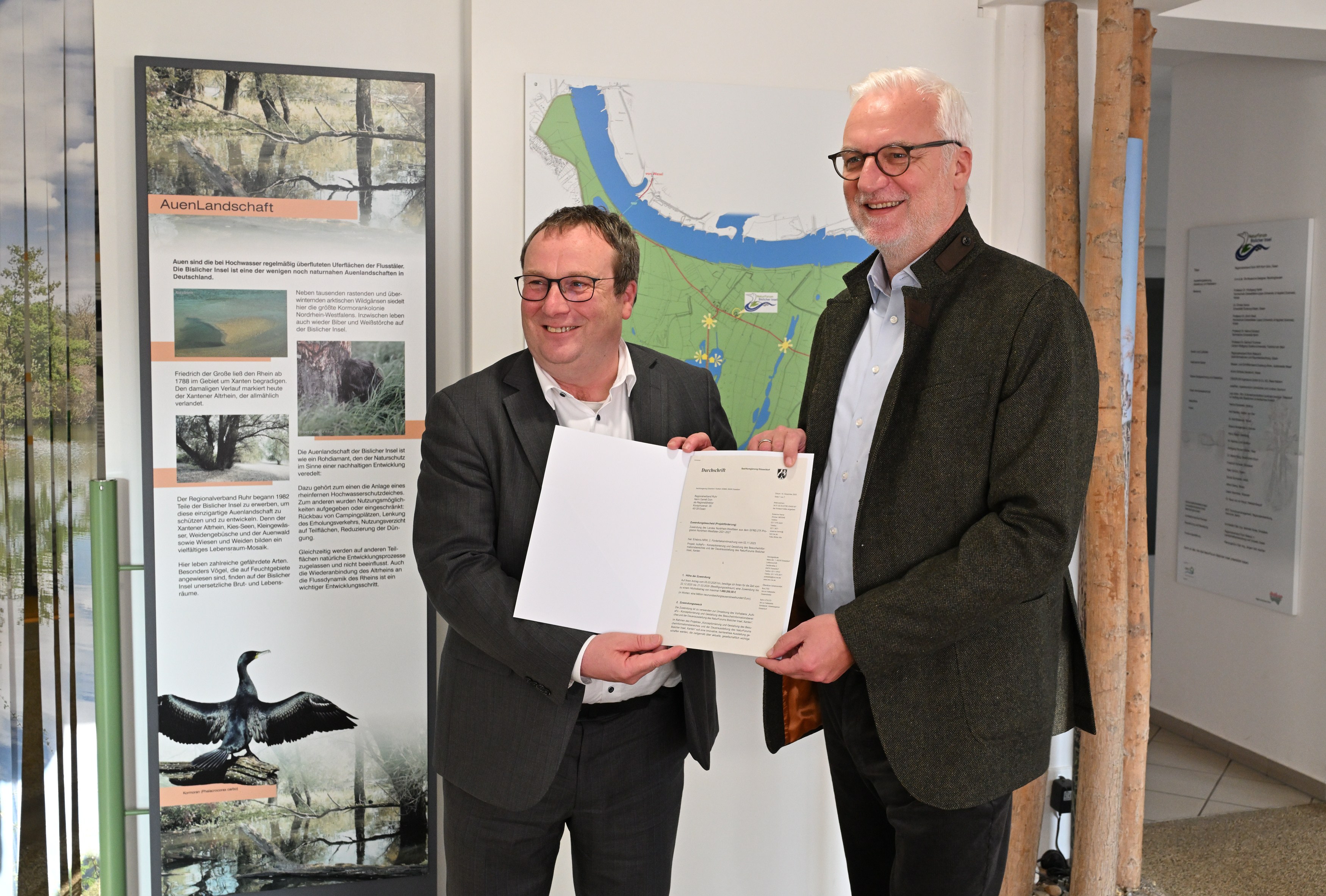NRW-Umweltminister Oliver Krischer (links) übergibt den Förderbescheid für die Weiterentwicklung des NaturForums Bislicher Insel in Xanten  an den Regionaldirektor des Regionalverbandes Ruhr Garrelt Duin. 