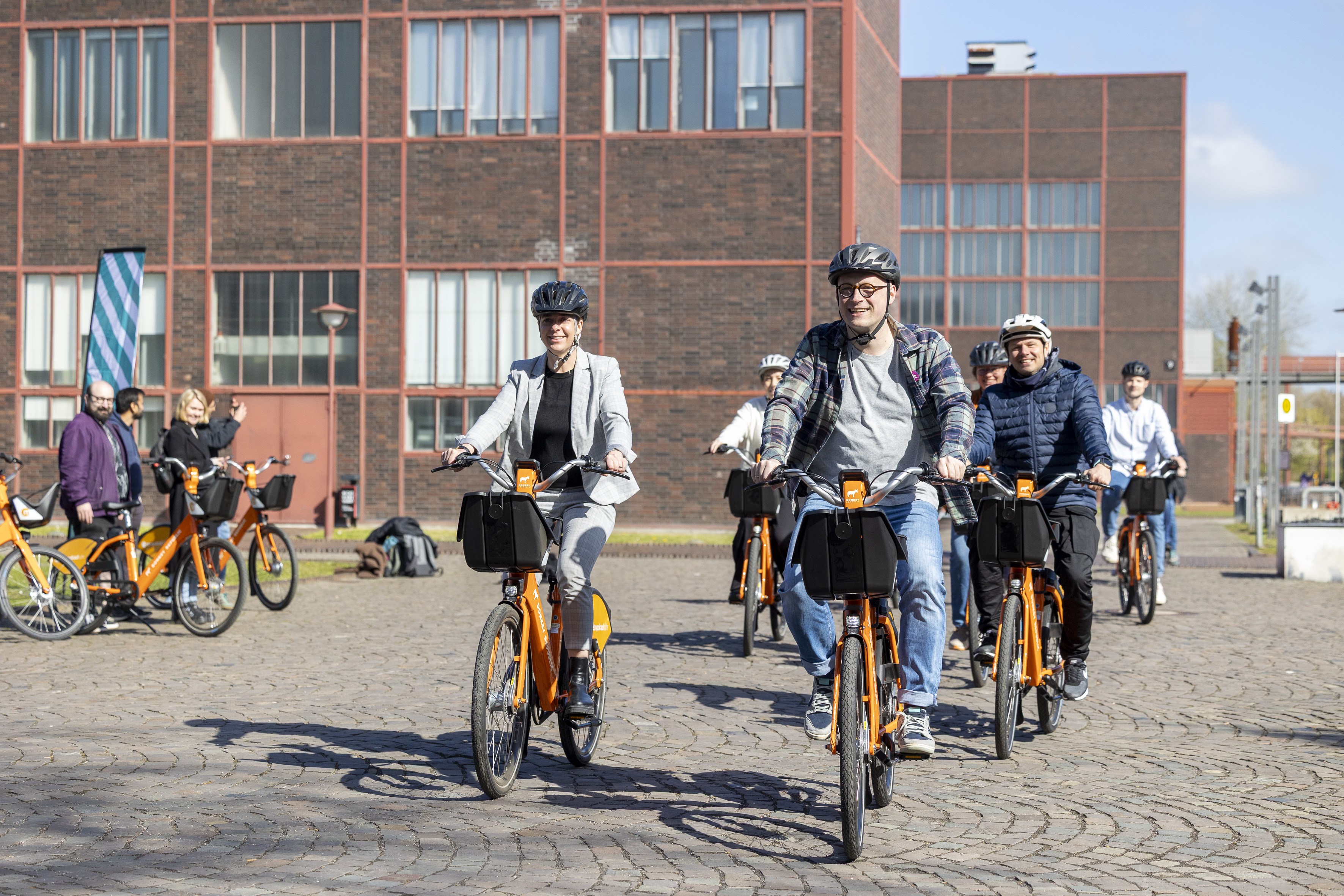 Unterwegs mit dem metropolradruhr Signe Storgaard Sørensen, Chief Operating Officer von Donkey Republic (l.), und Stefan Kuczera, RVR-Beigeordneter Regionale Planung und Entwicklung (vorne rechts) testeten die Räder auf dem Welterbe Zollverein in Essen.
