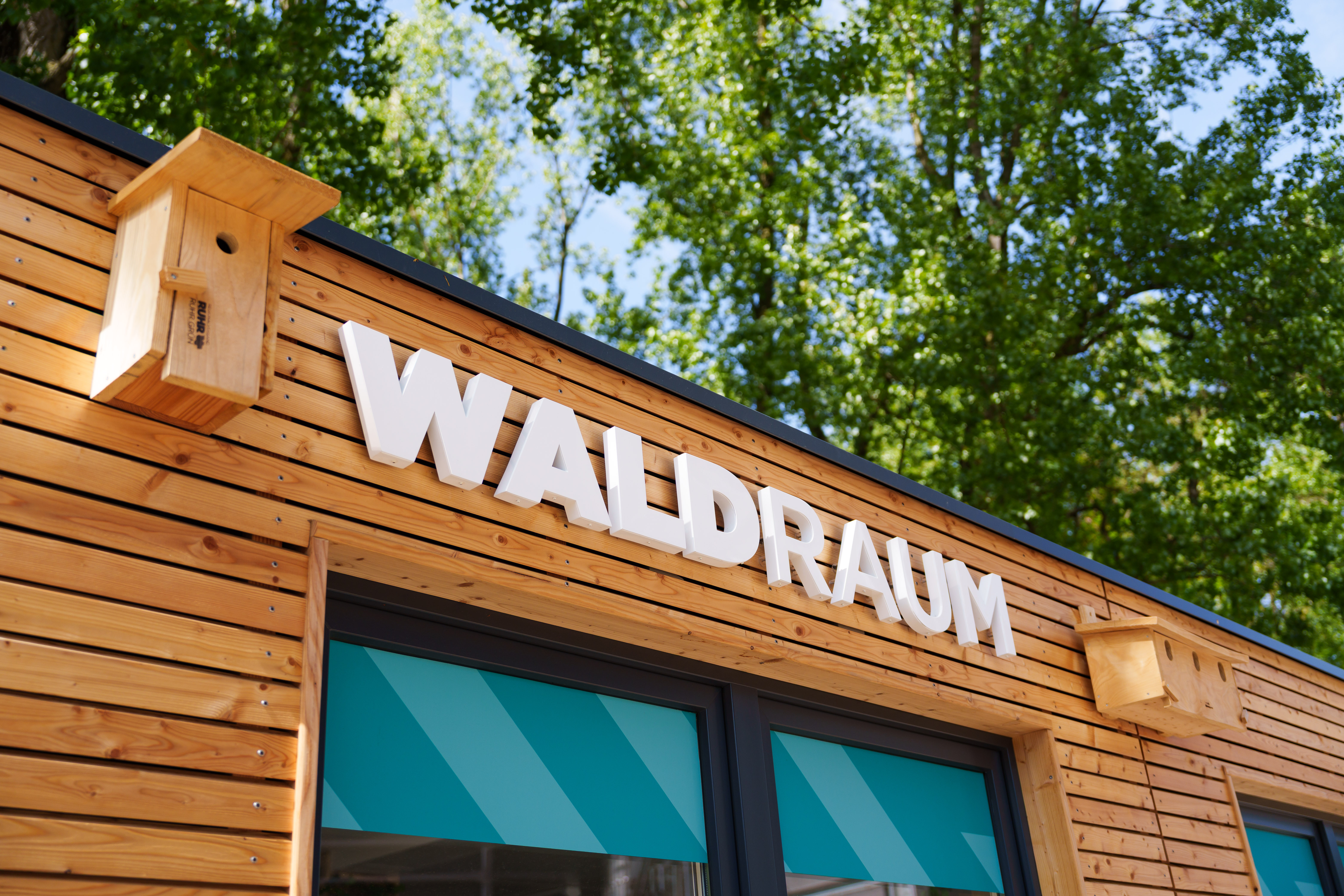 Holzfassade mit der Aufschrift: Waldraum
