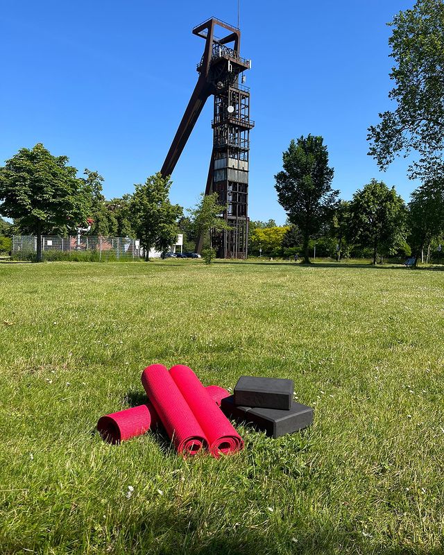 Yogamatten liegen auf der Wiese vor Schachtgerüst Recklinghausen II